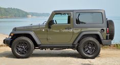 a green jeep parked on top of a sandy beach