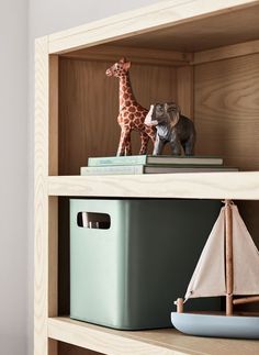 a toy boat and giraffe sitting on top of a book shelf