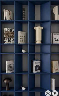 a blue book shelf filled with books next to a white vase and other items on top of it