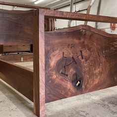 a wooden bed frame with a clock face on it's side in a warehouse