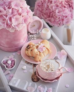 a tray with pink flowers and pastries on it, along with other items from the table