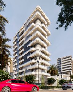 a red car is parked in front of a tall white building with balconies