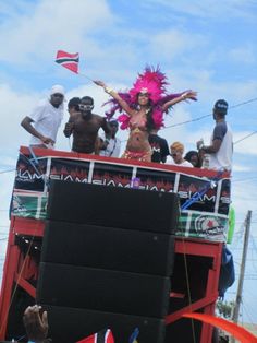 a group of people standing on top of a bus with a woman dressed in pink