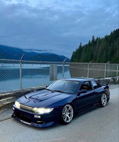 a blue car parked on the side of a road next to a body of water