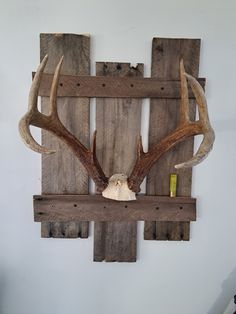 an antlers head mounted on the side of a wooden wall hanging from a wood plank