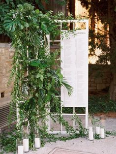 an outdoor ceremony with candles, greenery and seating chart for the guests to sit down