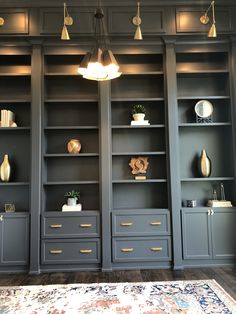 a living room filled with lots of gray bookshelves next to a white rug