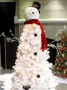 a white christmas tree with a snowman on top