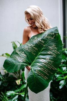 a woman holding a large green leaf with names on it