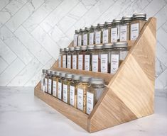 a wooden spice rack with six jars on it and one is filled with different types of spices