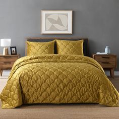 a bed with yellow comforter and pillows in a gray room next to two nightstands