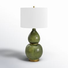 a green lamp sitting on top of a white table next to a white lampshade