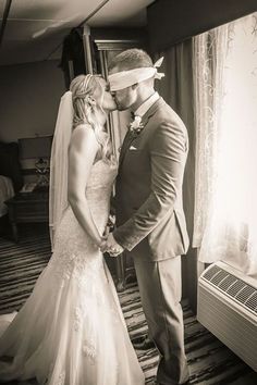 a bride and groom standing in front of a window