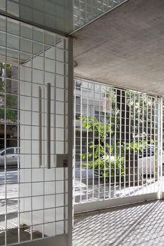 an empty room with white tile walls and metal bars on the doors, in front of a parking lot