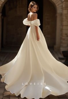 a woman in a white wedding dress standing on a brick walkway with her back to the camera