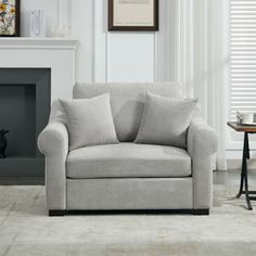 a living room scene with focus on the couch and chair in front of the fireplace