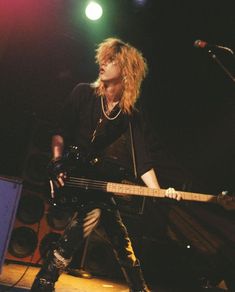 a man with long hair playing guitar on stage