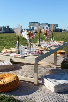 the table is set with flowers and place settings on it for an outdoor dinner party