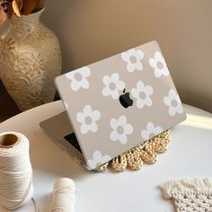 an apple laptop sitting on top of a table next to yarn and spools