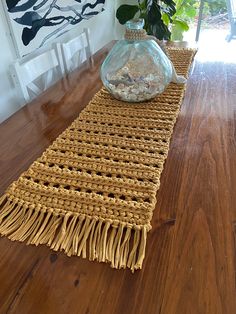 a wooden table topped with a glass vase filled with water and rocks on top of it