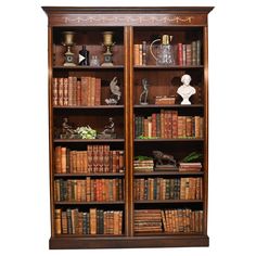 an old bookcase with many books on it and some statues in the back ground