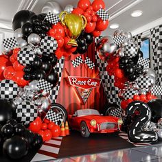 a red car surrounded by black and white balloons with a gold trophy on top in front of it