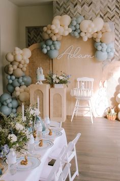 a table set up with white and blue balloons