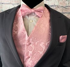 a man in a tuxedo is wearing a pink bow tie and black jacket