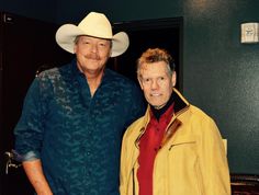 two men standing next to each other wearing cowboy hats