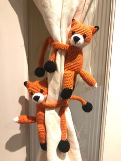 two stuffed animals hanging from the side of a curtain