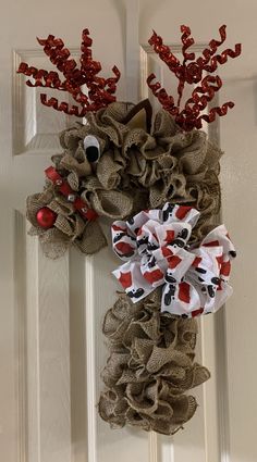 a door hanger decorated with burlocks and red berries