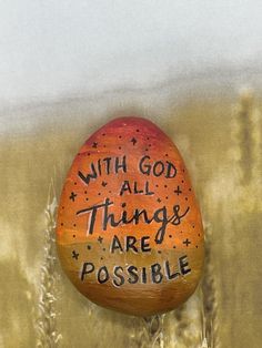 an orange painted rock with the words with god all things are possible written on it