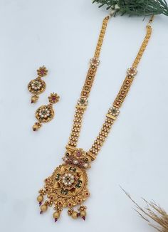 This Antique Gold Plated Long Necklace & Drop Earring Indian Jewelry Set is a timeless piece designed to bring out the elegance and grace of traditional Indian jewelry. The long necklace features intricate designs plated in antique gold, enhanced with shimmering Cubic Zirconia (CZ) stones for a luxurious touch. Paired with matching drop earrings, this set is perfect for weddings, festivals, or any grand occasion. The antique finish adds a vintage charm, making it an ideal choice for those who ap Long Indian Necklace, Indian Jewelry Set, Indian Bridal Jewelry Sets, Necklace Set Indian, Necklace Indian, Indian Necklace, Gold Jewelry Sets, Antique Gold Jewelry, Indian Jewelry Sets