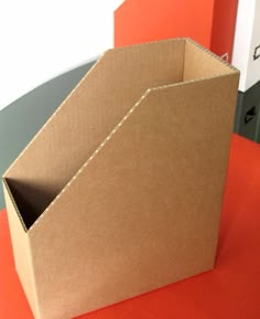 an open cardboard box sitting on top of a red table next to a file cabinet