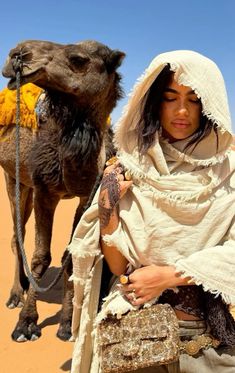 a woman in white is standing next to a camel