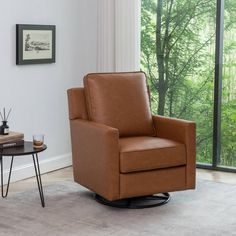 a living room with a chair, table and window overlooking the trees in the background