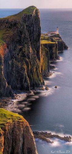 the lighthouse is perched on top of the cliff by the water's edge, overlooking the ocean