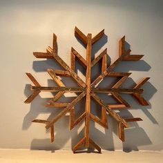 a wooden snowflake sitting on top of a white table next to a wall