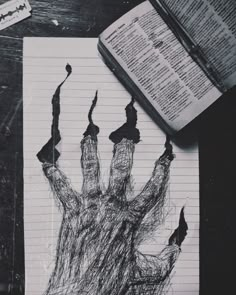 a drawing of a hand on top of a piece of paper next to an open book