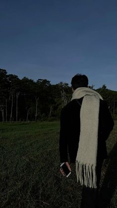 a man standing in the grass wearing a white scarf