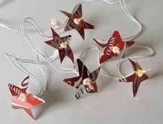 some red and white stars are hanging from the side of a light fixture that says soda can star lights