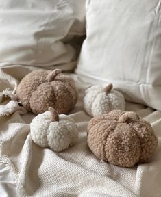 three crocheted pumpkins sitting on top of a bed next to white pillows