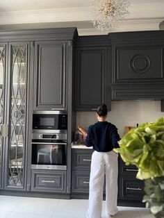 a woman standing in front of a kitchen counter with an oven and microwave on it