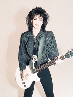 a woman with black hair holding a white guitar