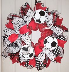 a red and black soccer wreath hanging on a door with polka dot ribbon around it