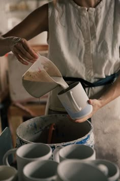 a woman is pouring something into a cup