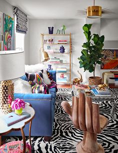 a living room filled with lots of furniture and decor on top of a zebra print rug