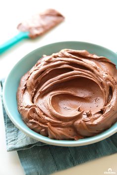 a blue bowl filled with chocolate frosting on top of a table