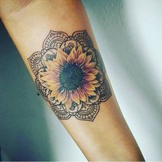 a sunflower tattoo on the arm with an intricate pattern around it's center