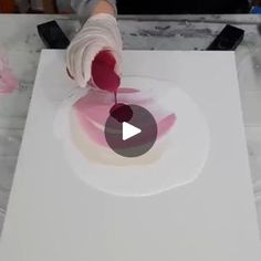 someone is painting on a white surface with pink and red colors in the background,